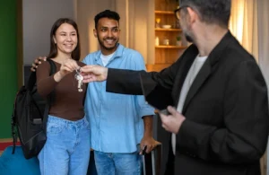 Casal recebendo um chaveiro das mãos de um corretor.