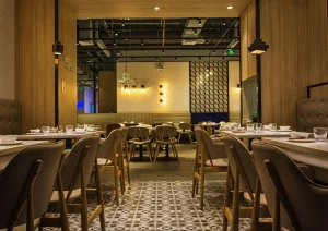 Restaurante sofisticado com ambiente moderno, mesas bem arrumadas, cadeiras confortáveis e iluminação aconchegante, transmitindo elegância e boa experiência gastronômica.