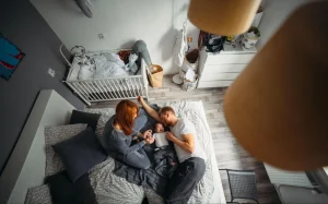 Vista aérea de casal com bebê recém-nascido no quarto de bebê em apartamento moderno.